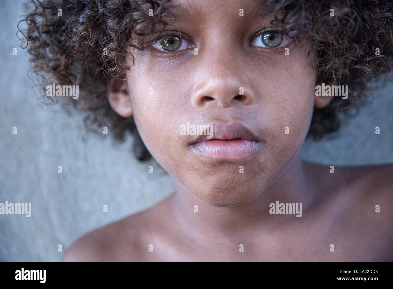 Beautiful boy with green eyes, curly hair and tan skin Stock Photo