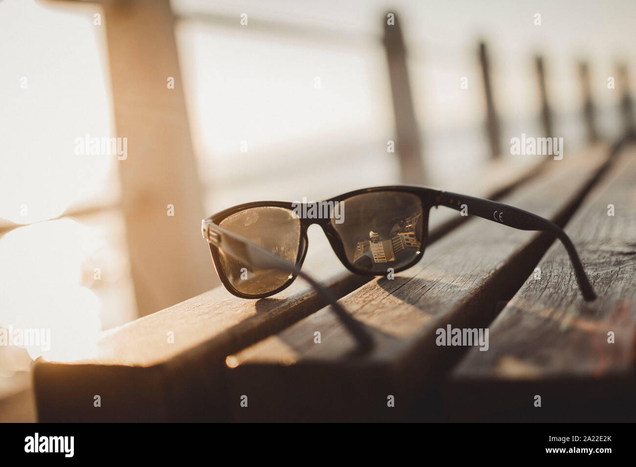 sunglasses on a bench at sunset Stock Photo