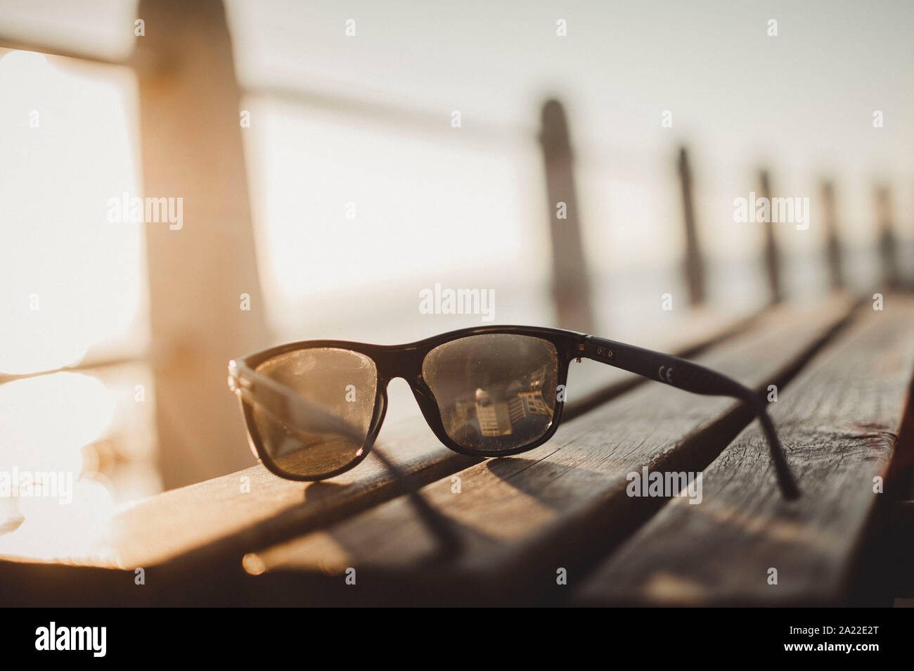 sunglasses on a bench at sunset Stock Photo