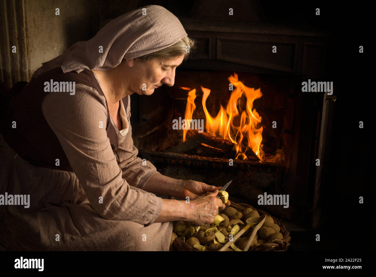 Renaissance old master portrait of a peasant woman peeling potatoes at her fireplace Stock Photo
