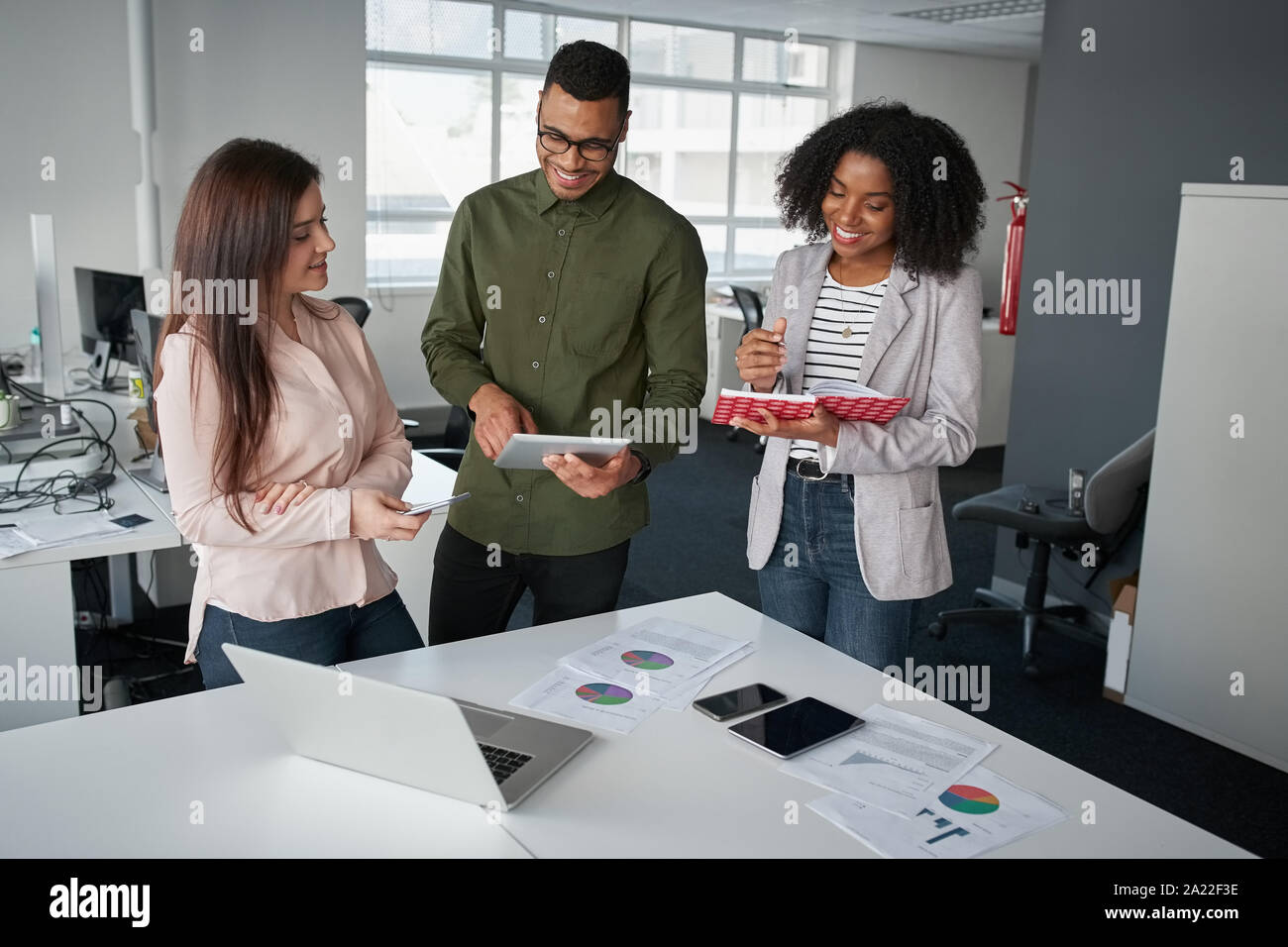 Multiethnic coworkers team working new startup project at modern office analyzing business documents, using digital tablet and mobile phone Stock Photo