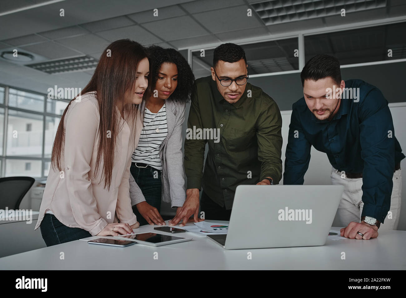 Group of smart young multiethnic businesspeople discussing ideas while looking at laptop computer Stock Photo