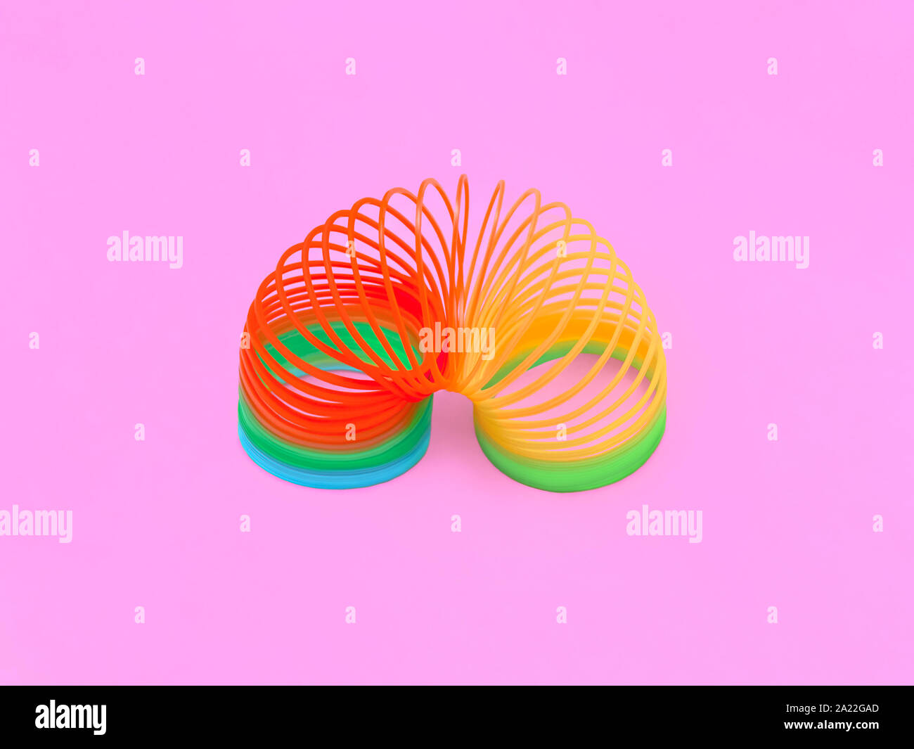 Spring toy Front view Bright slinky toy on a pink background Minimal style Stock Photo