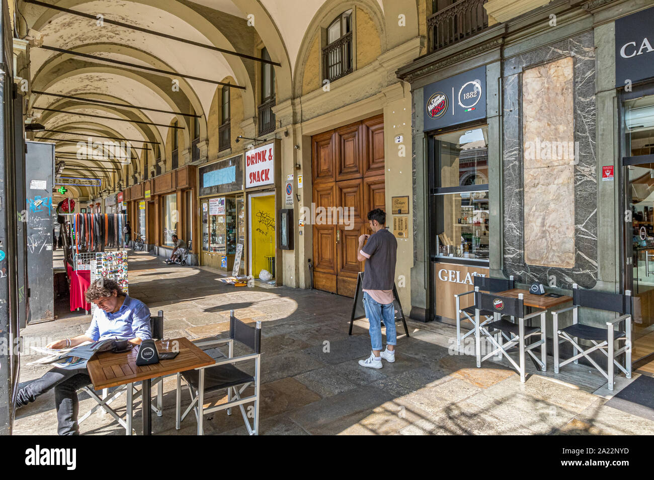 A man reading a newspaper and having coffee at a table at Bar Sacchi  under the colonnaded shopping arcades along Via Sacchi ,Turin ,Italy Stock Photo
