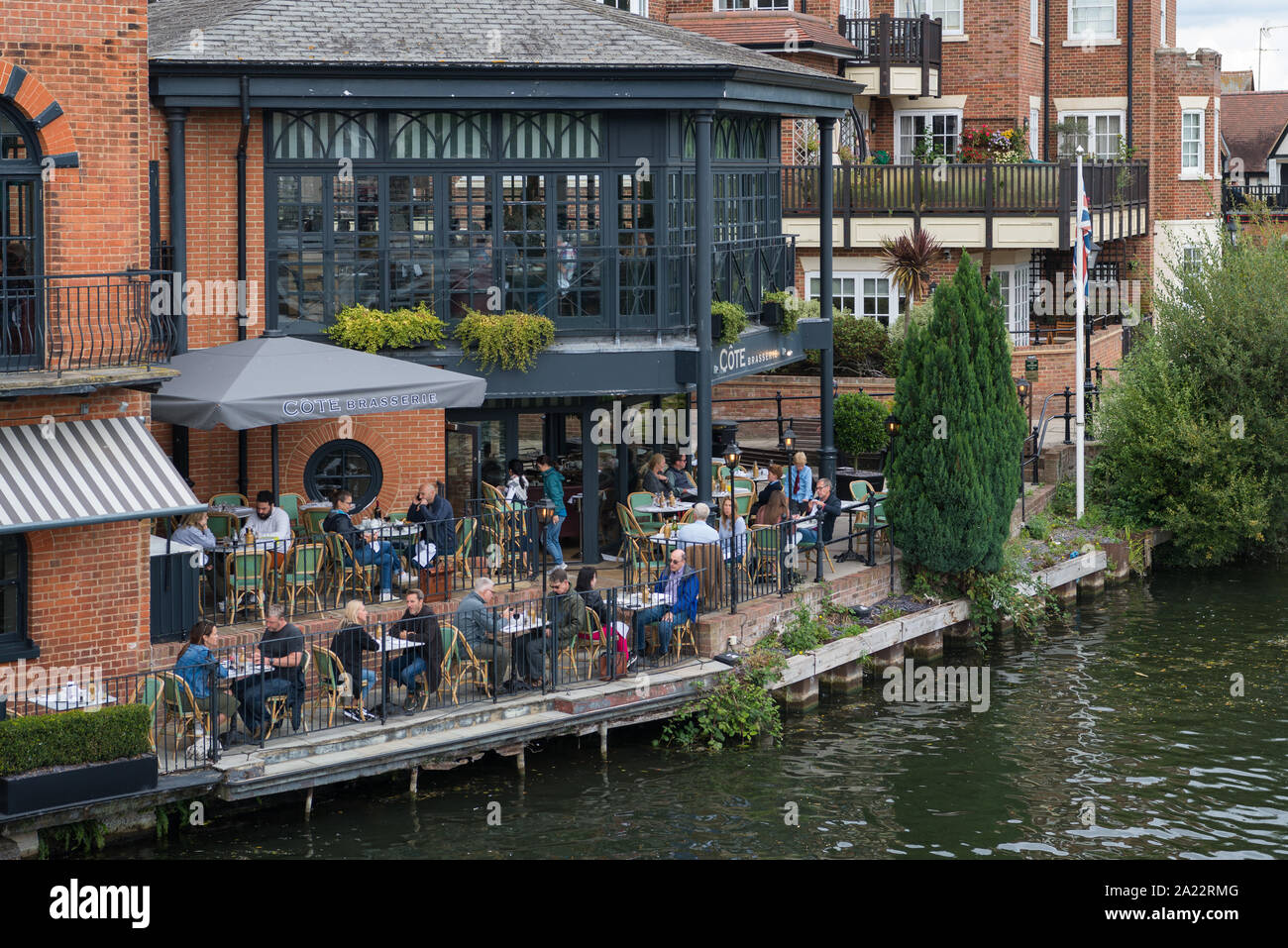 People socialising and enjoying food and refreshments at the Cote Brasserie French restaurant on the bank of the River Thames at Eton, Berkshire, UK Stock Photo