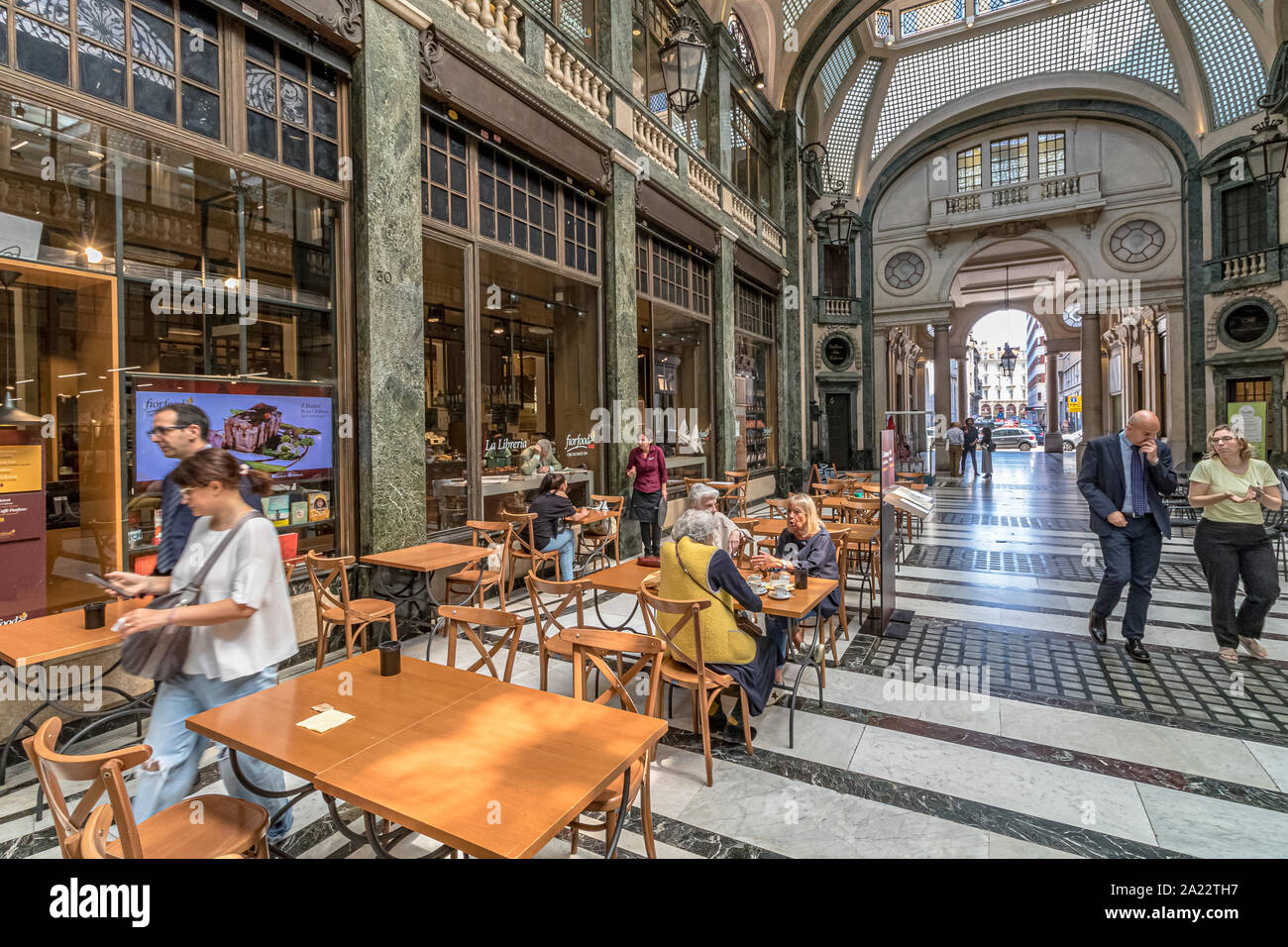 People sitting at tables eating food in the indoor ,art deco,glass ceilinged arcade ,Galleria San Federico in Turin ,Italy Stock Photo