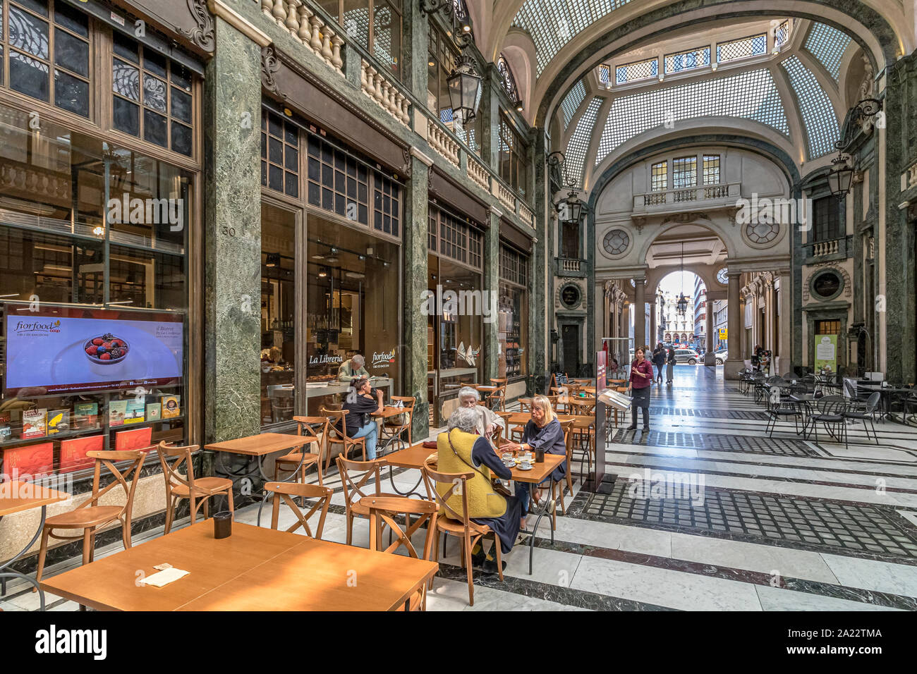 People sitting at tables eating food in the indoor ,art deco,glass ceilinged  arcade ,Galleria San Federico in Turin ,Italy Stock Photo