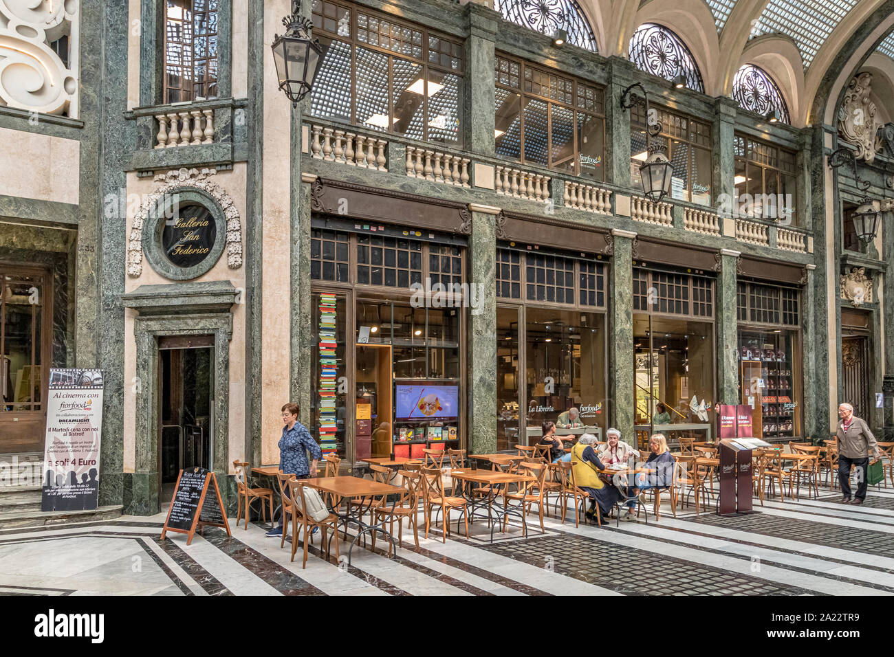 People sitting at tables eating food in the indoor ,art deco,glass ceilinged arcade ,Galleria San Federico in Turin ,Italy Stock Photo