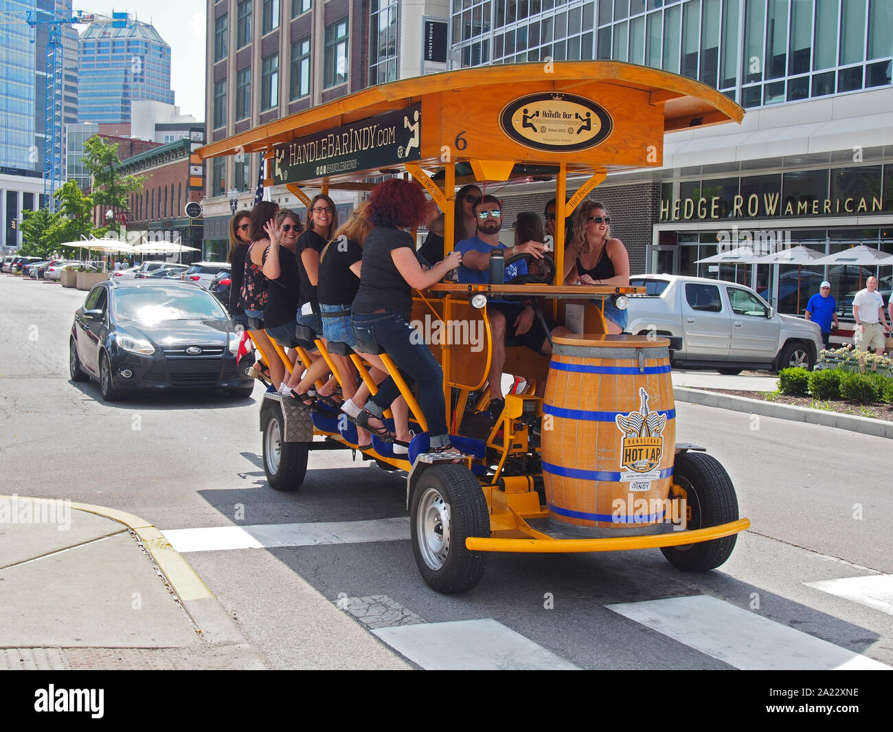 A group of women having fun and drinking beer while pedaling the bicycle pub Handlebar Indy along Mass Ave, one of the six designated cultural distric Stock Photo