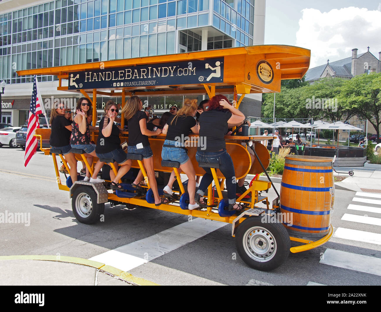 A group of women having fun and drinking beer while pedaling the bicycle pub Handlebar Indy along Mass Ave, one of the six designated cultural distric Stock Photo