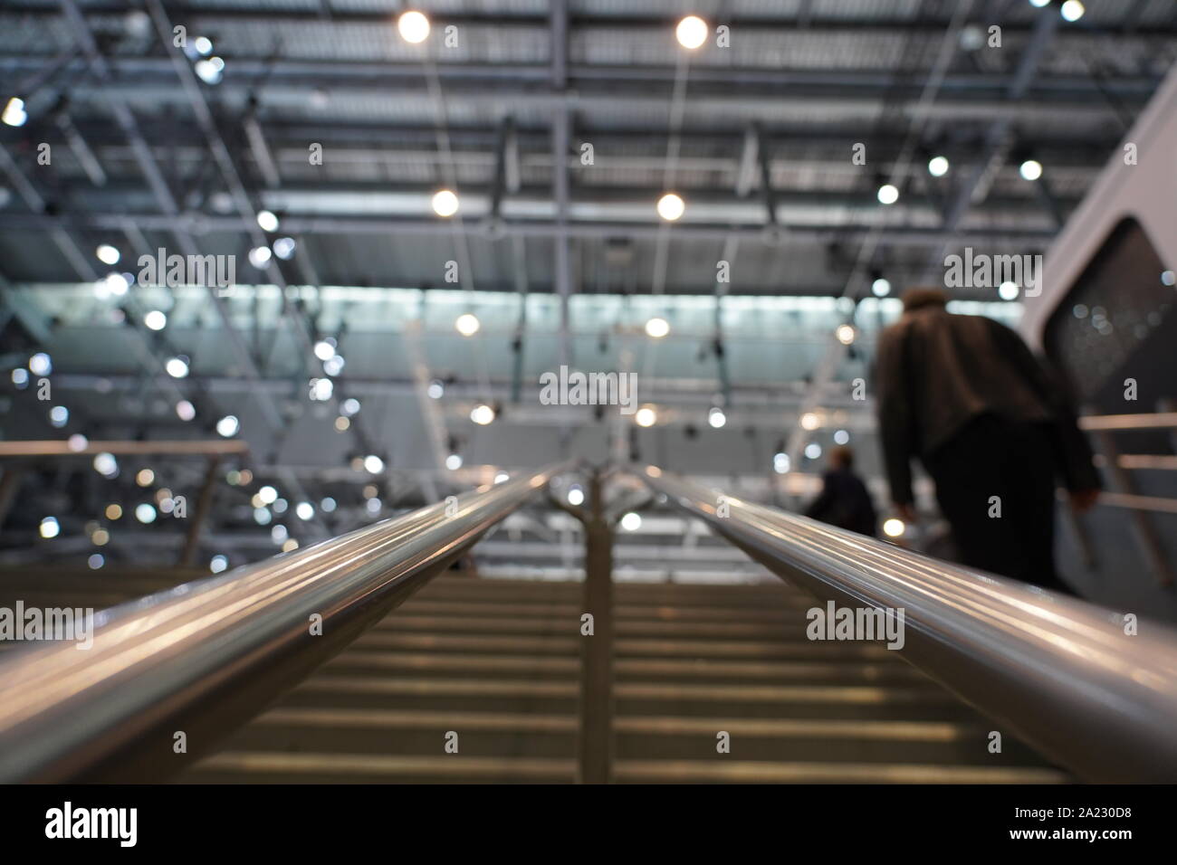 Iron handles of stairs with blurred light on the ceiling and visitors climbing up the stairs to the swiss Autosalon Genf 2019 in Geneva, Switzerland Stock Photo
