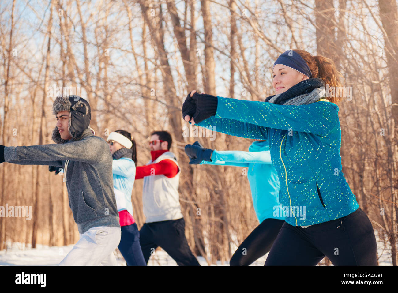 Group of millenial young adult friends stretch and strengthen in a snow filled park Stock Photo
