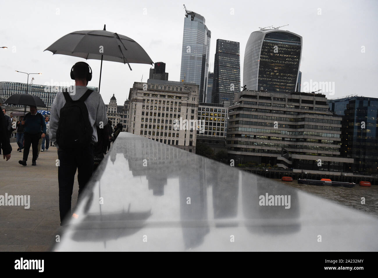 Commuters cross London Bridge, as parts of Britain brace for two more days of heavy downpours, ahead of some snowfall and the leftovers of a hurricane later this week. Stock Photo
