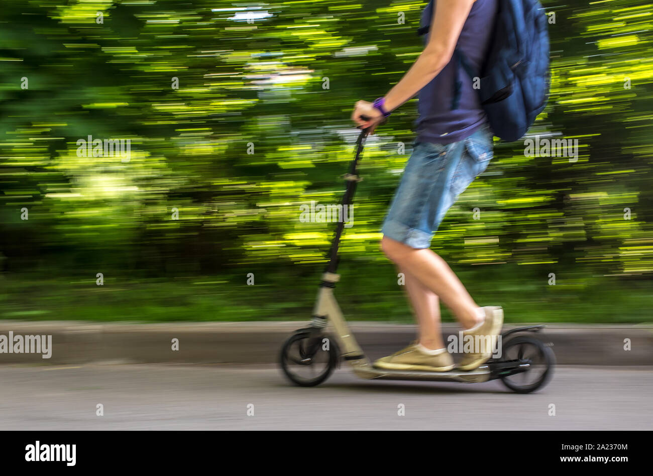 female rides a scooter at speed down the road, blurred background the