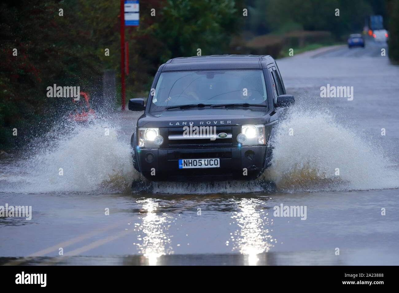 A Land Rover makes a splash as it drives through a flooded section of ...