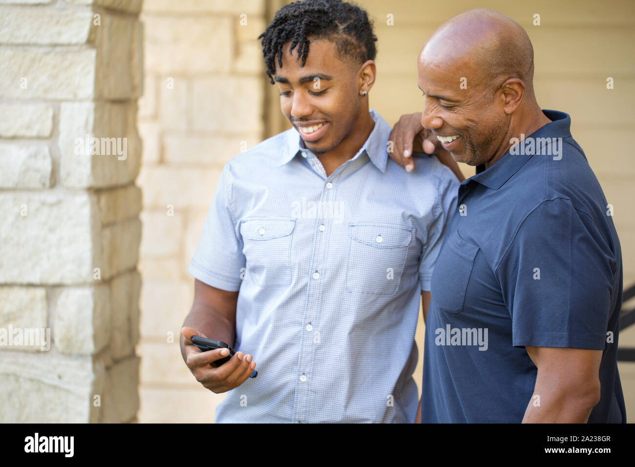 African American father and his adult son texting. Stock Photo