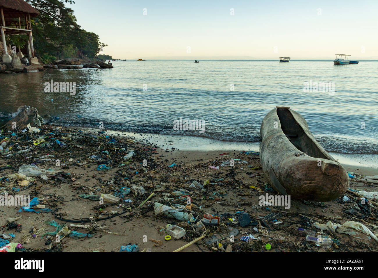 Plastic pollution on the shores of Lake Malawi, near Nkhata Bay, alongside a traditional hand-carved canoe Stock Photo