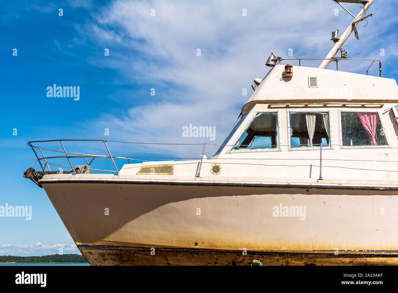 Old white boat shot sidewise against blue sky. Nose of white yacht, side view. Stock Photo