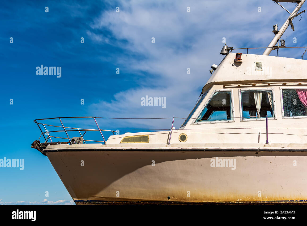 Old white boat shot sidewise against blue sky. Nose of white yacht, side view. Stock Photo