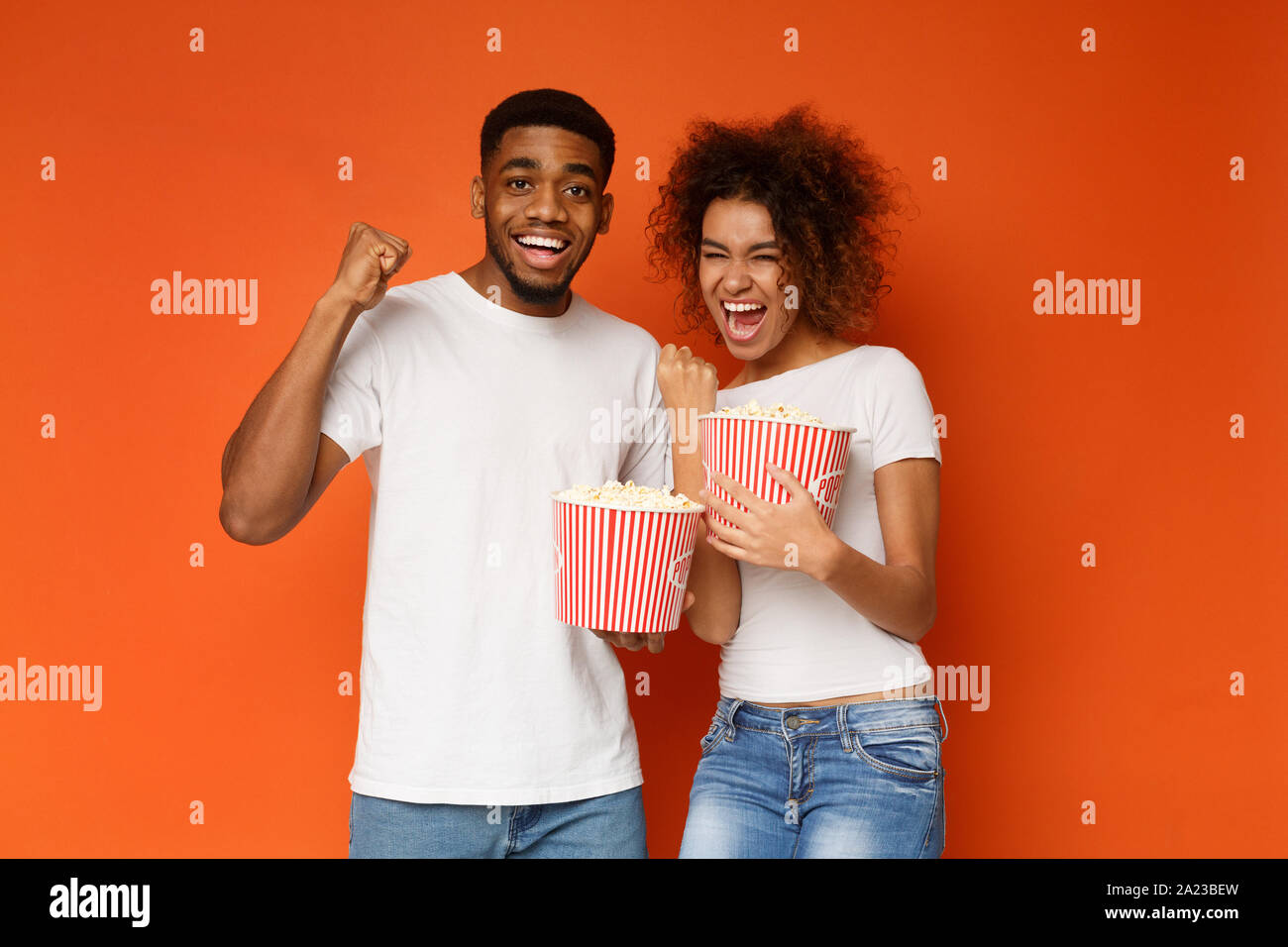 Cheat meal. Emotional black couple enjoying movie with buckets of