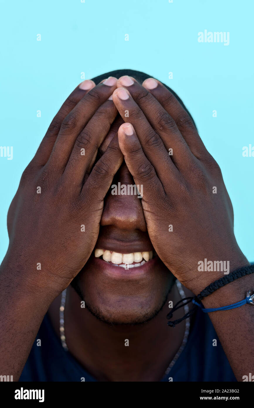 Portrait of an african man covering his face with hands Stock Photo - Alamy