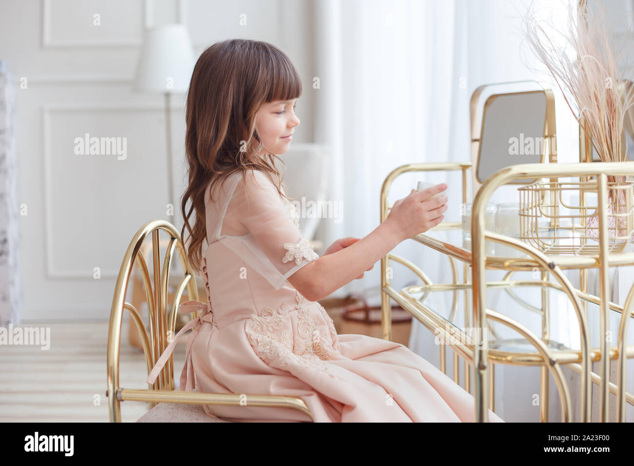 Cute little girl near oval mirror at dressing table Stock Photo