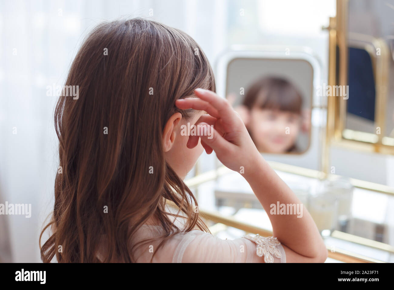 Cute little girl near oval mirror at dressing table Stock Photo