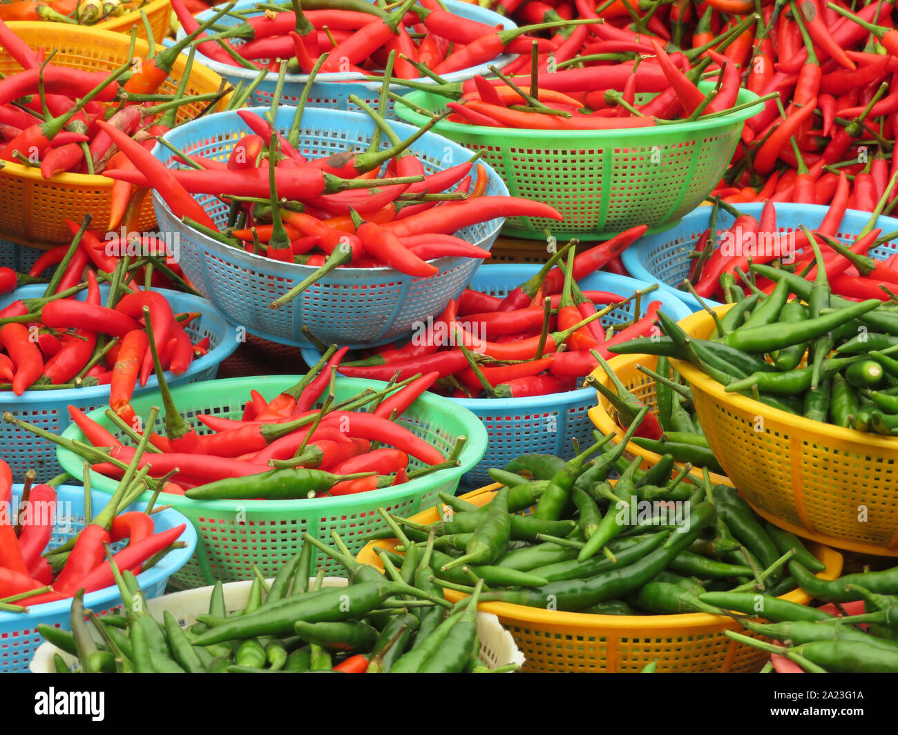 Red and green chili peppers in baskets. Hot spices at the street market in Thailand Stock Photo
