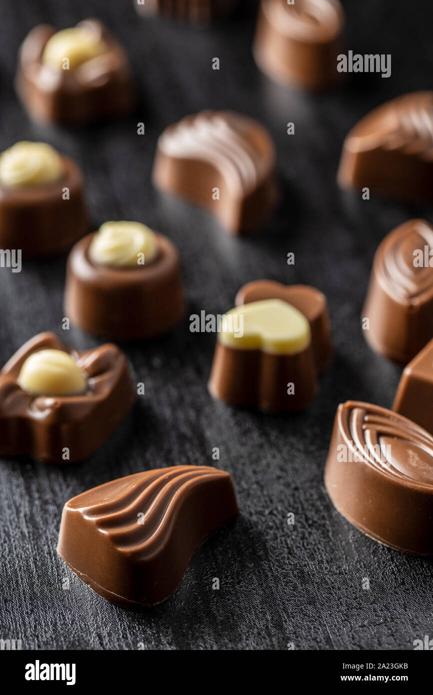 Various chocolate pralines on black table. Stock Photo