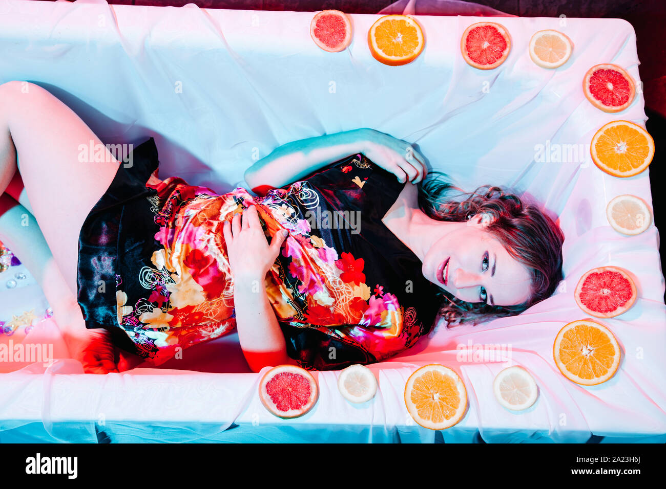 Young woman relaxing in Spa bath with slices of oranges. Welness