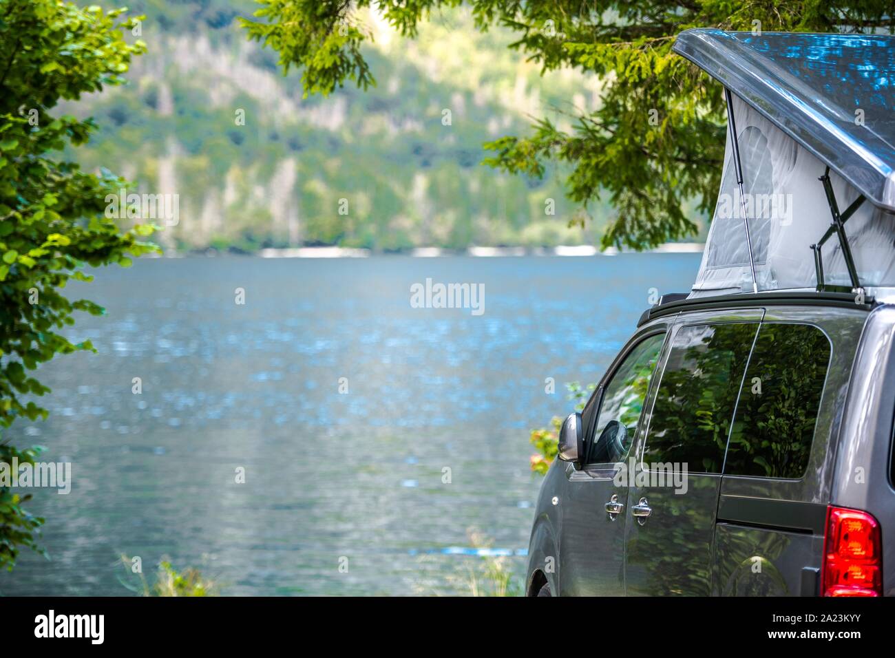 Lake Camping in the Van Rooftop Tent. Modern Camper Van in the Scenic Mountain Location. Stock Photo