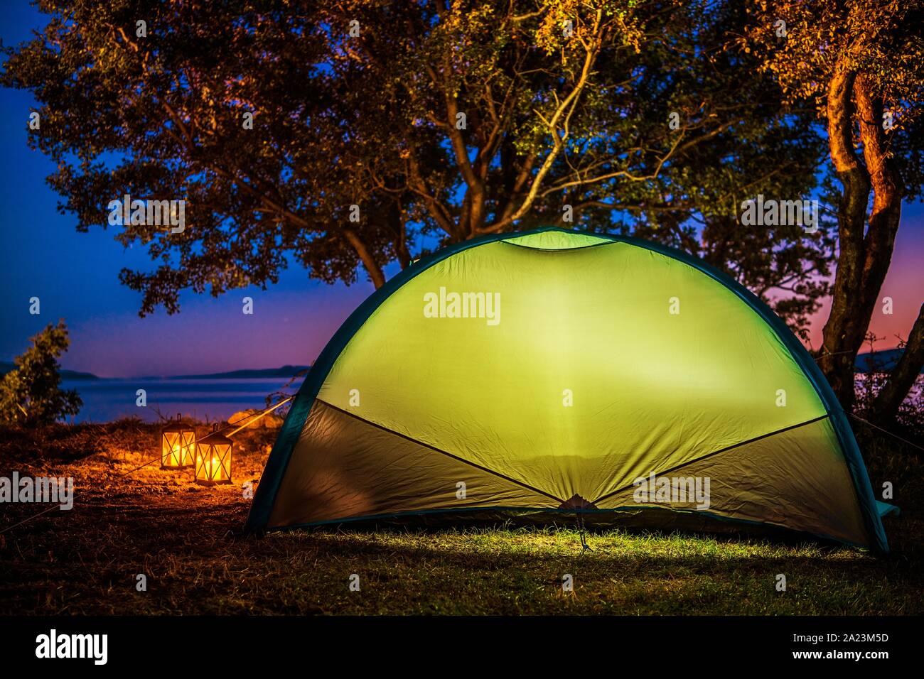 Sea Front Tent Camping. Glowing Light Inside Small Modern Tent. Campground and Outdoor Theme. Stock Photo