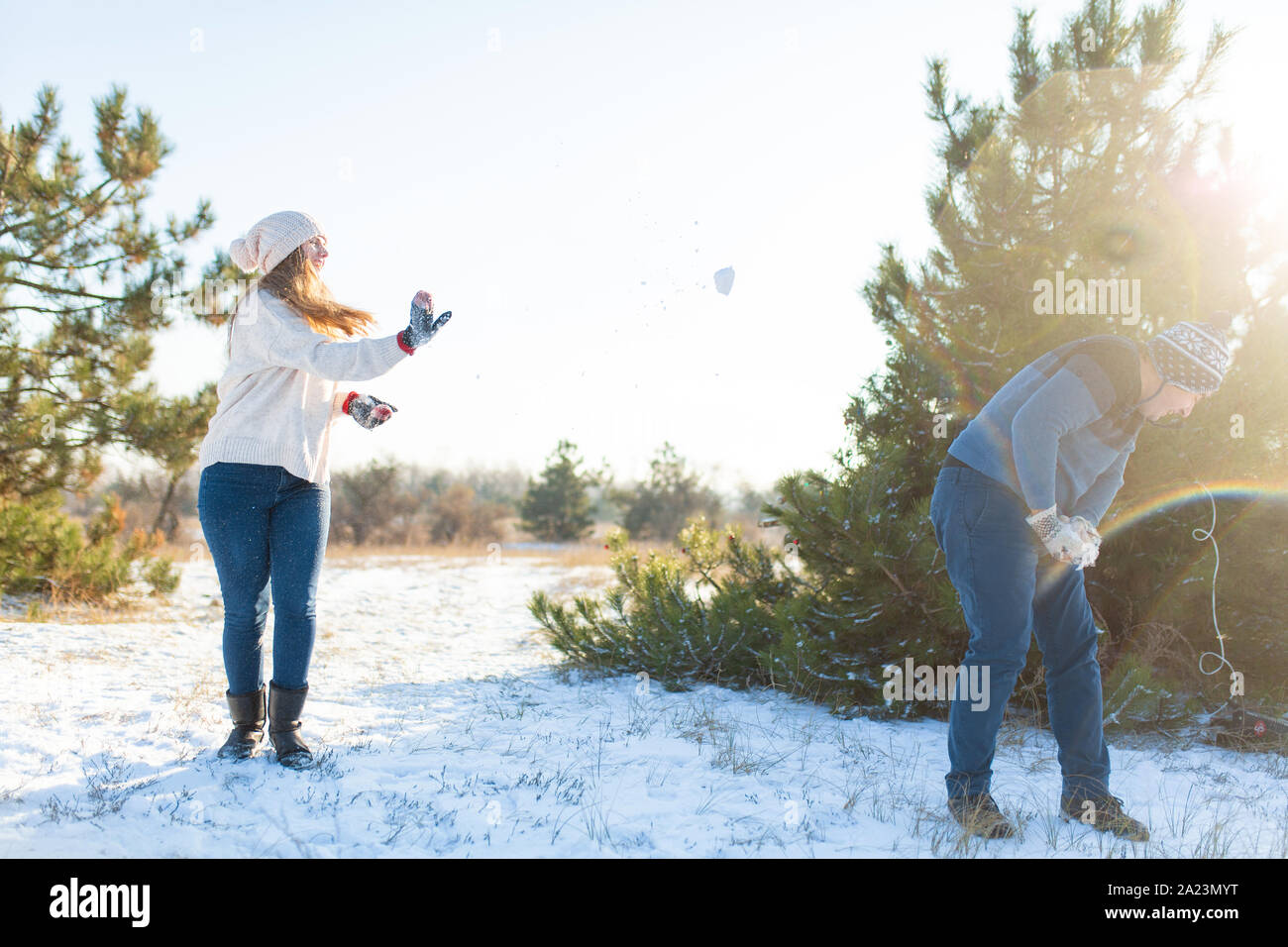 Loving couple play snowballs in winter in the forest. Throw each other ...