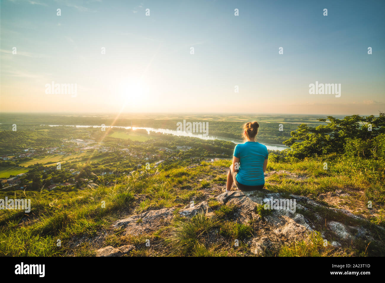 A Girl Sits on the Edge of the Cliff and Looking at the Sunset and the ...