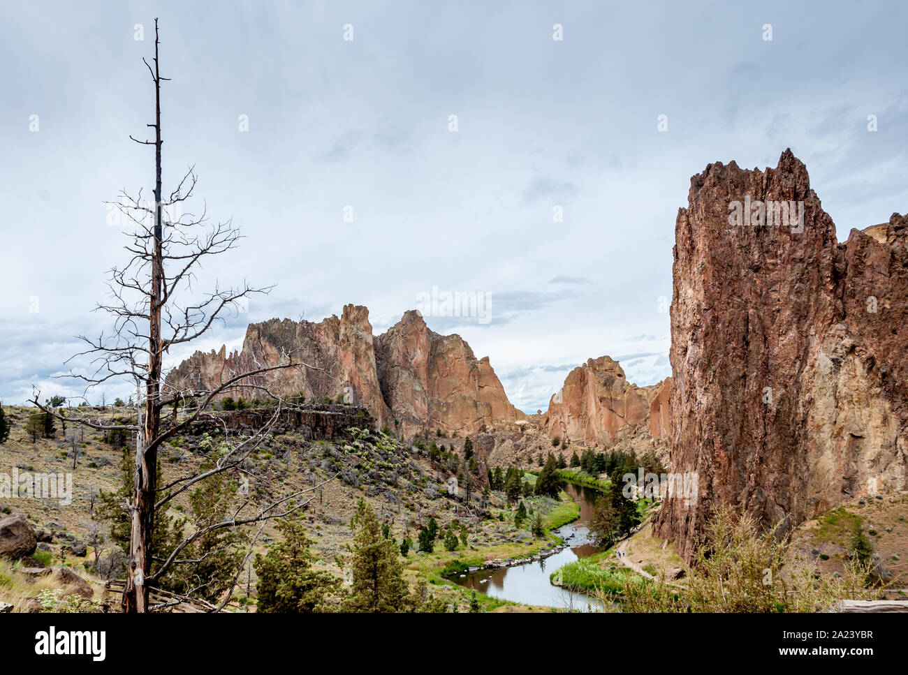 Smith Rock State Park establishing shot, landscape overview with Crooked River, Cathedral Rock, high cliffs clouds in sky. Stock Photo