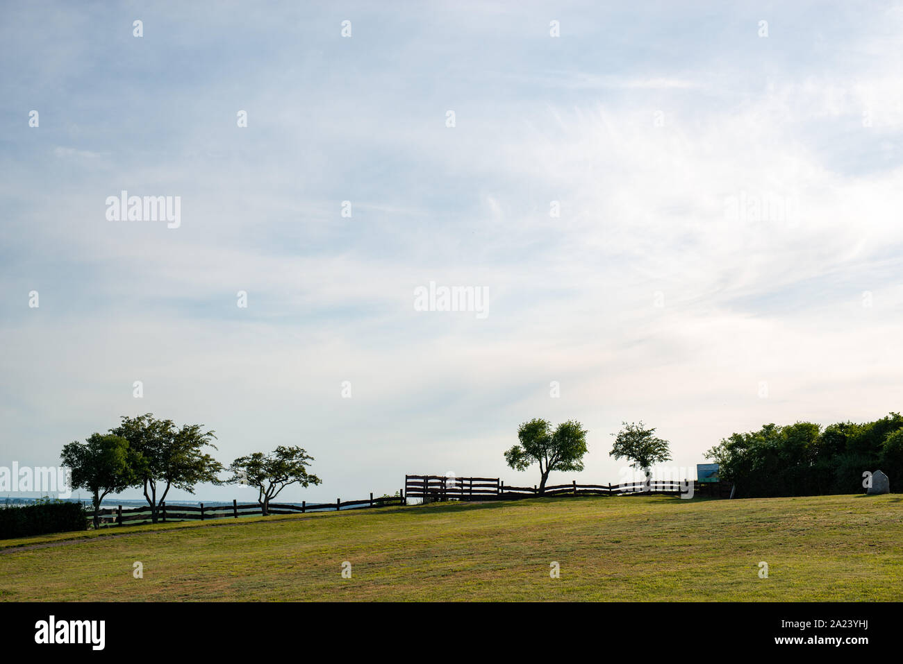 Cliff line at National Wolinski Park in Poland. Trees on meadow in background. Wooden fence. Sunlight. Stock Photo