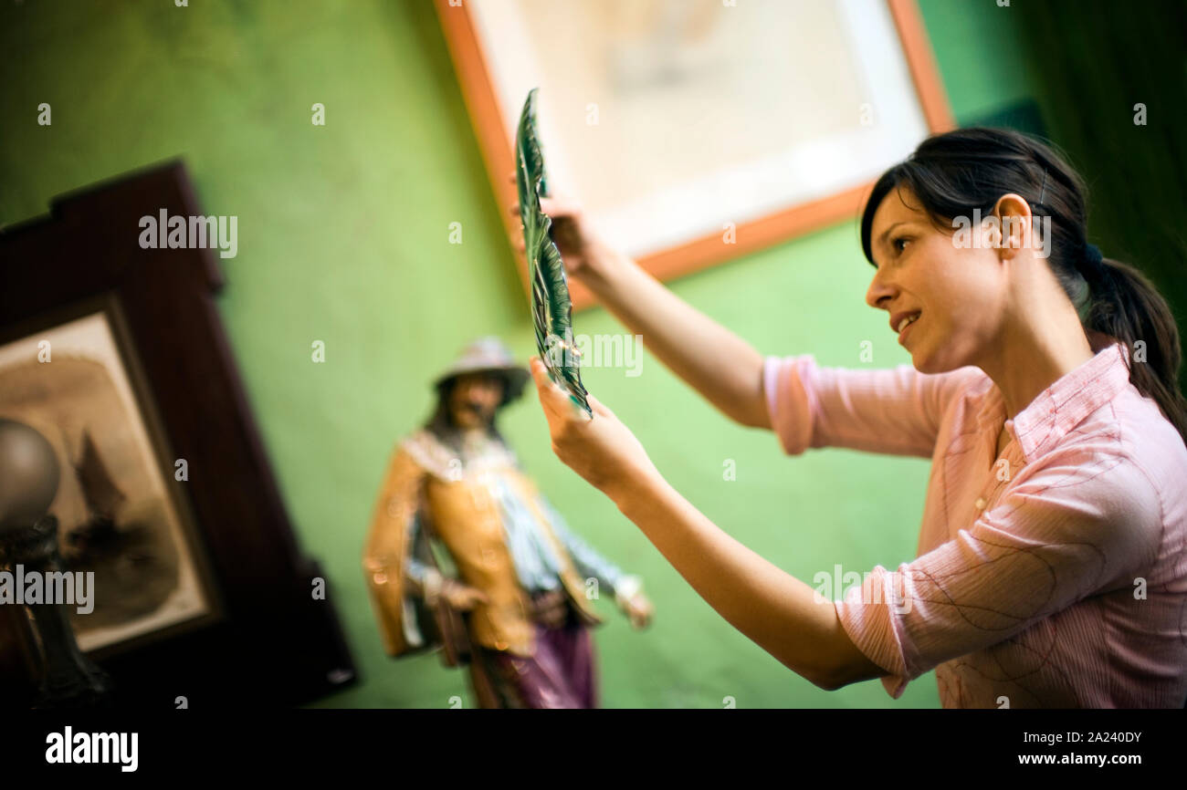 A woman thoughtfully looks at a decorative piece. Stock Photo