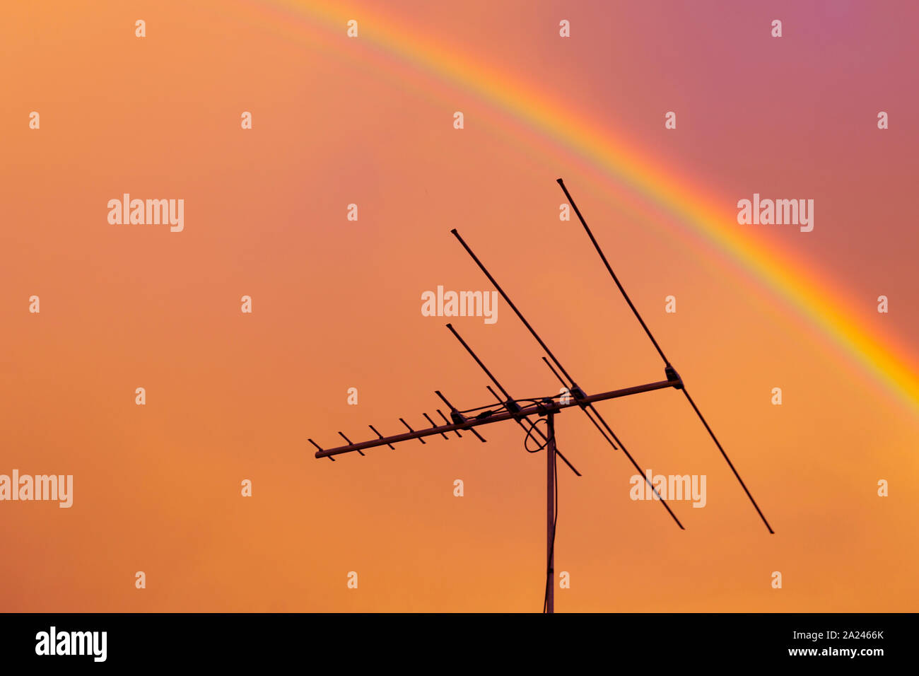 Residential tv antenna pointing directly through rainbow overhead Stock Photo Alamy