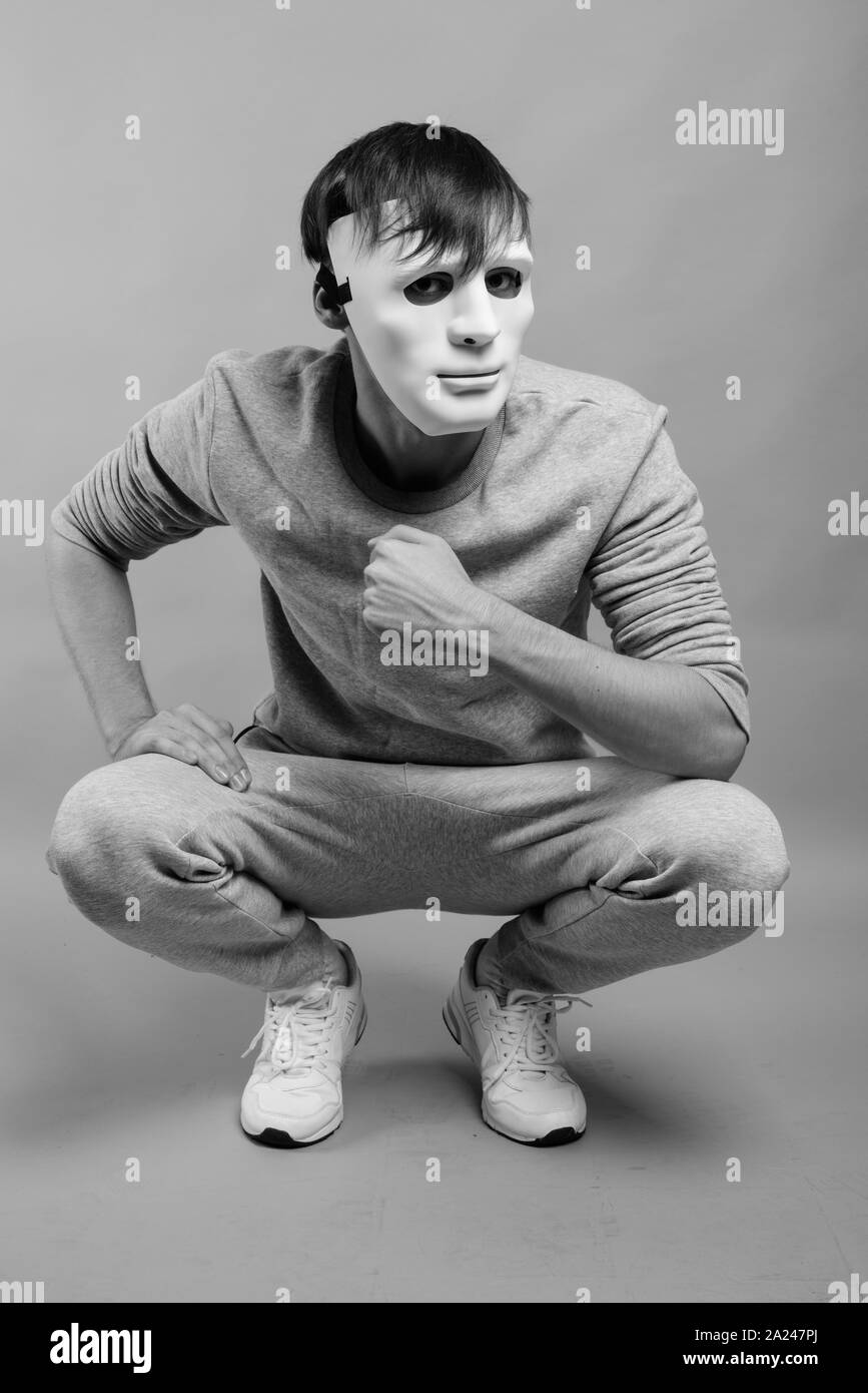 Young handsome man wearing white mask against gray background Stock Photo