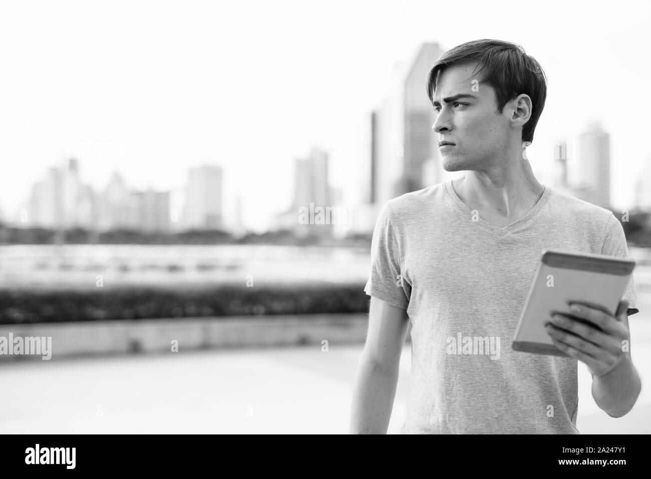 Young handsome man using digital tablet while relaxing at the park Stock Photo