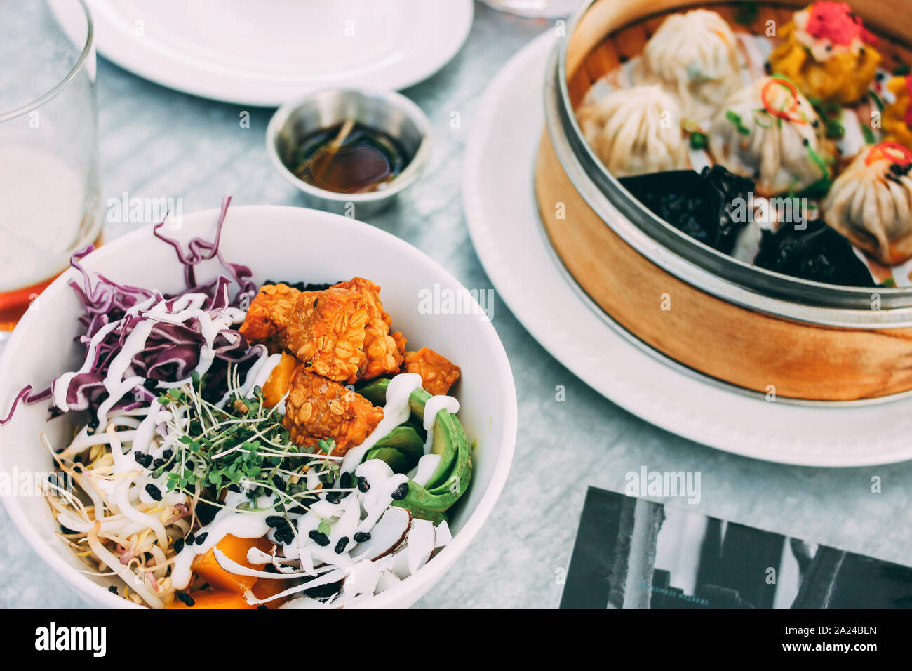 Pan-Asian food - vegetable salad bowl and different dim sums. Lunch for two with beer Stock Photo