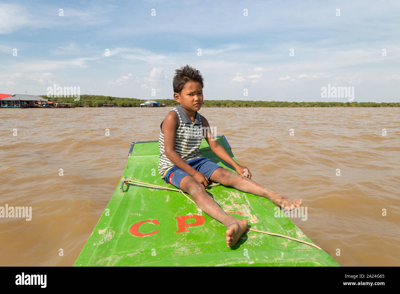 Siem Reap, Cambodia - January 31, 2017: Cambodian poor boy sitting on old tourist boat in the river Stock Photo