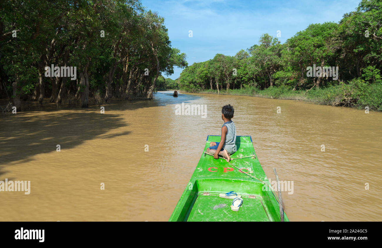 Siem Reap, Cambodia - January 31, 2017: Cambodian poor boy sitting on old tourist boat in the river Stock Photo