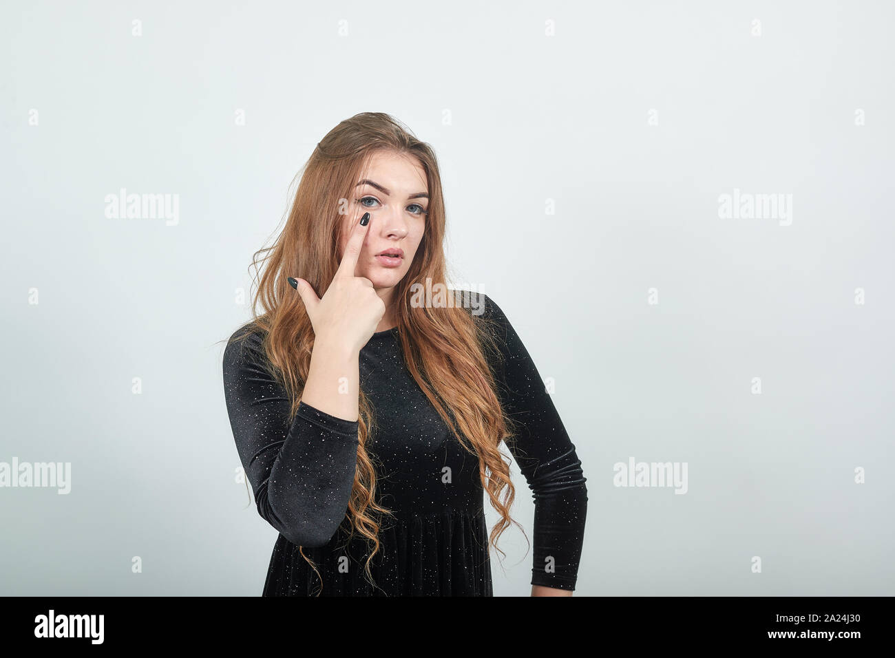 girl brown haired in black dress over isolated white background shows emotions Stock Photo