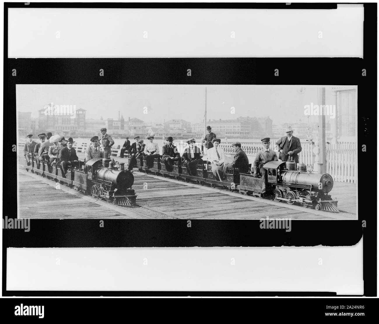 People on two miniature railroad trains on bridge or pier, possibly at Dreamland, Coney Island, New York City Stock Photo