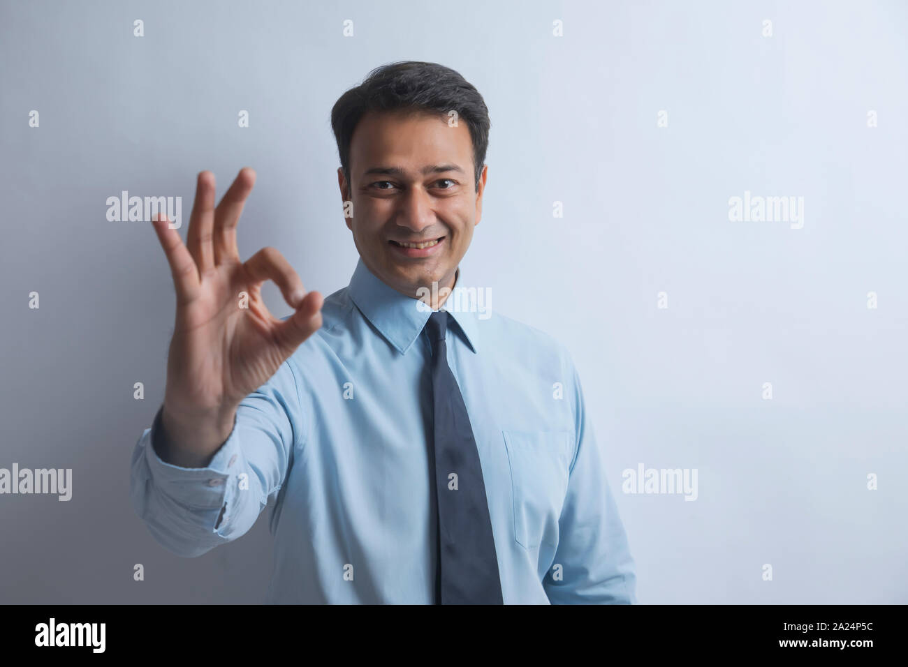 Smiling businessman in formal clothes making a hand gesture expressing good Stock Photo