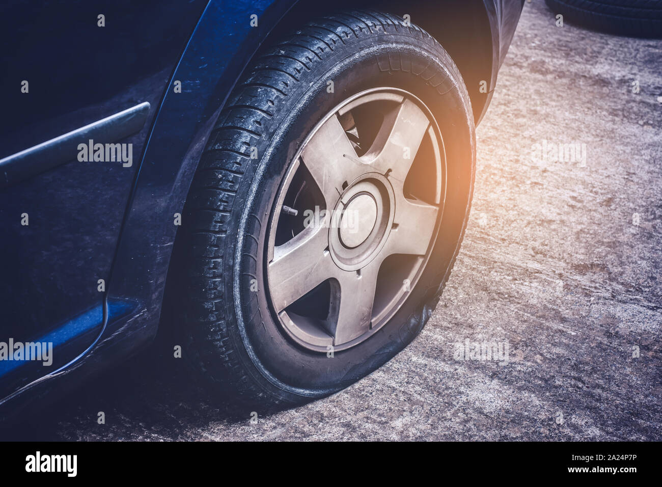 Close up of flat rear tire of a car punctured by screw Stock Photo