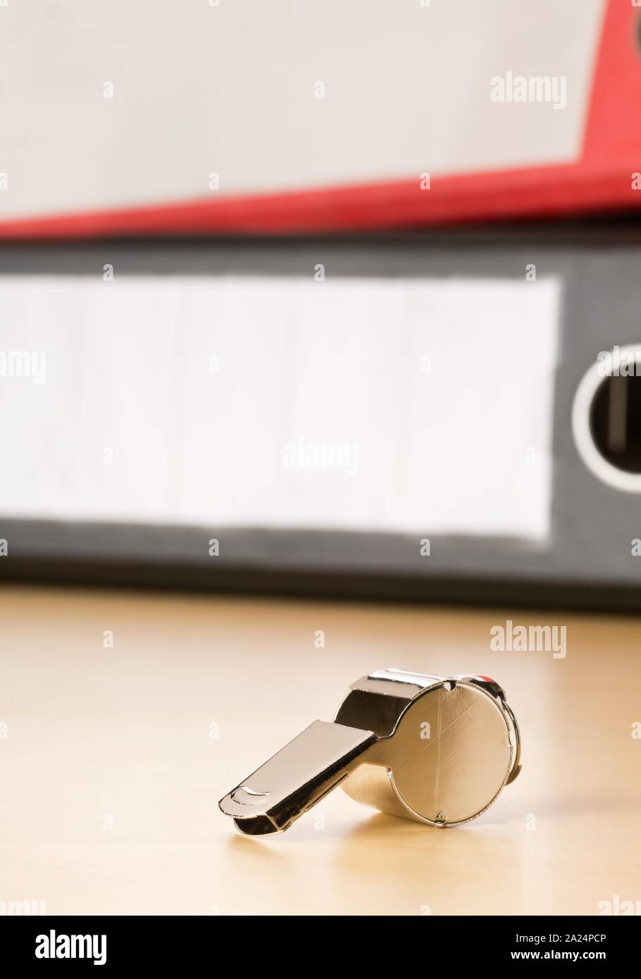 Chrome whistle in front of folders with confidential top secret