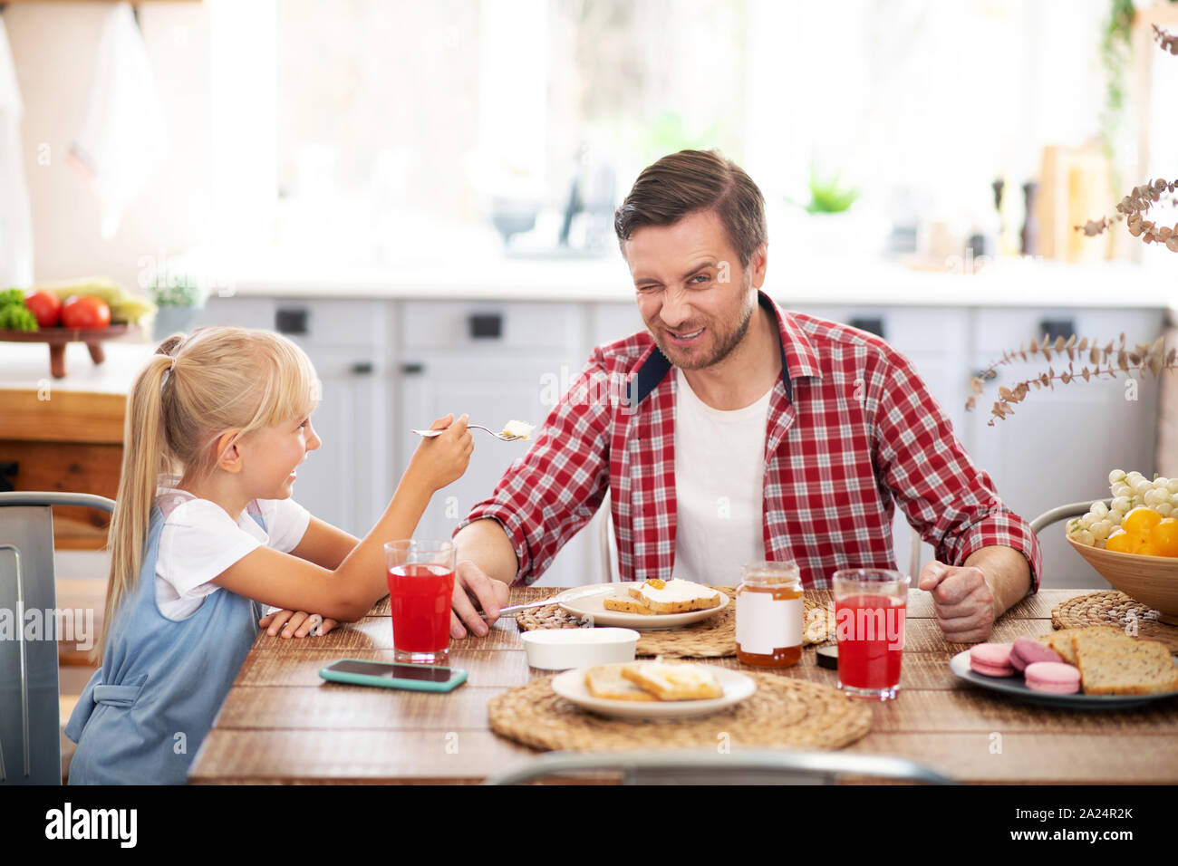 Father and daughter laughing while eating breakfast together Stock Photo Alamy