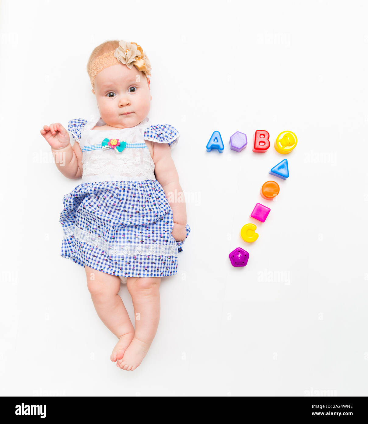 Portrait of a sweet infant baby girl wearing a pink dress and headband ...